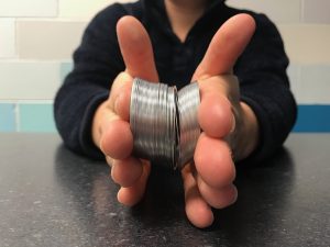 Two hands holding a broken slinky so that it is contracted