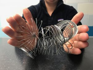 The same two hands holding the same slinky tangled up and twisted. 