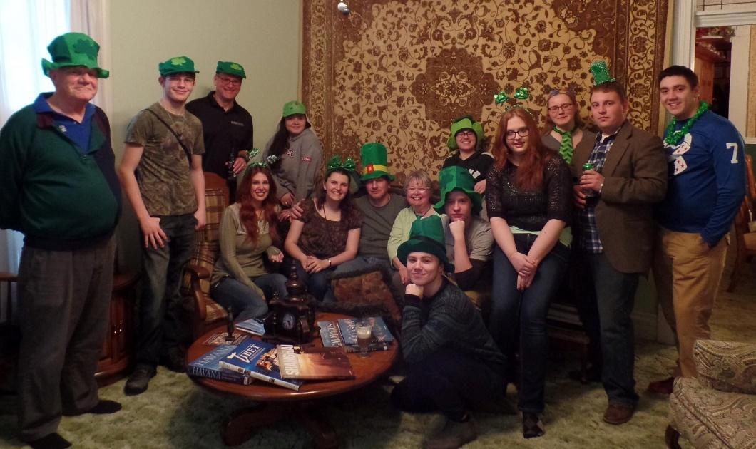 A group of people sitting around a table wearing green hats.