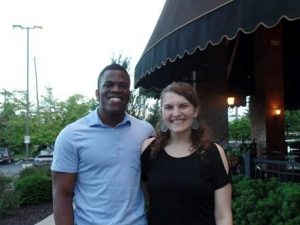 A man and a woman smiling into the camera outside a restaurant.