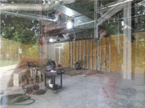 The insides of a coffee shop under construction is visible, as is the author's reflection in the glass.