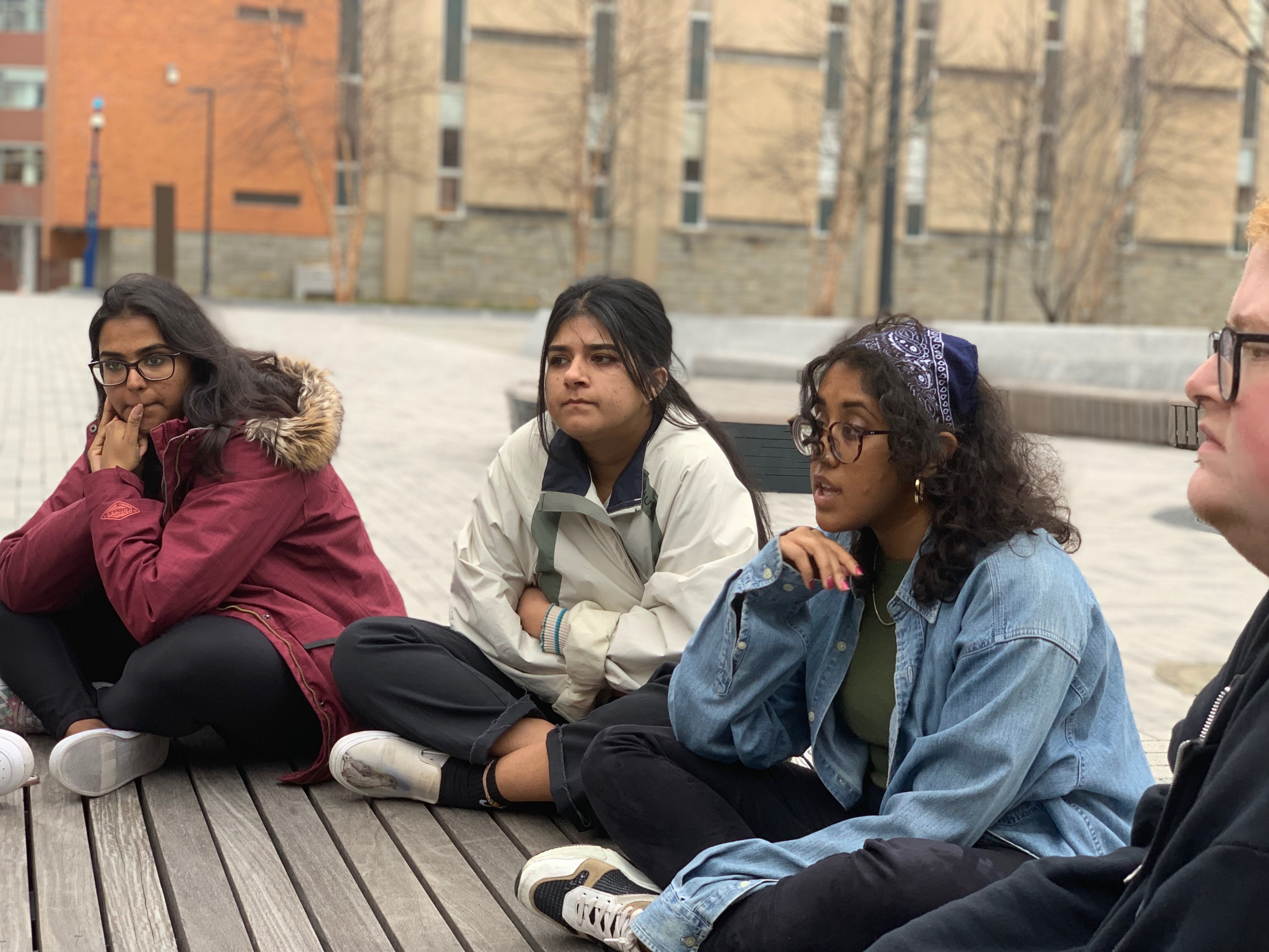 Image 5 - This photo shows Peer Readers in the process of working with ECCD. They are sitting outside, in a quad, and are a racially diverse group.
