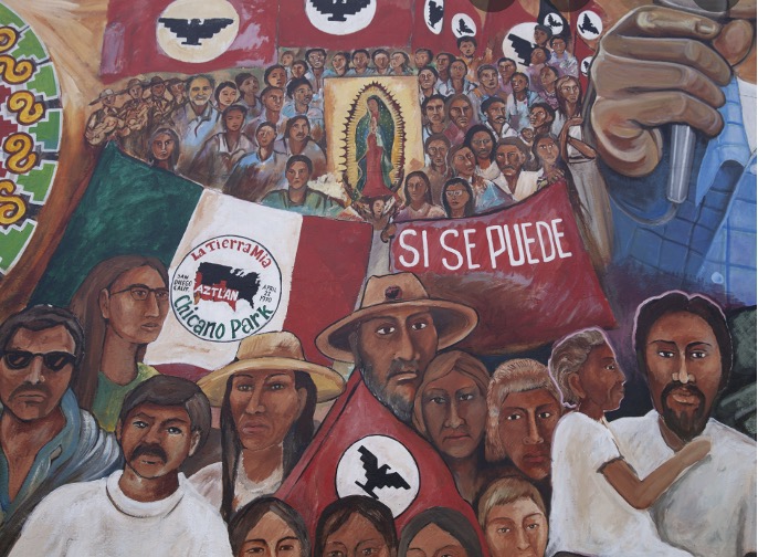 Painting of a group of people gathered with a flag that reads, “La Tierra Mia… Chicano Park” [translation into English: My Land…. Chicano Park”] and another flag that reads “SI SE PUEDE” [translation to English: “It is possible”]. 